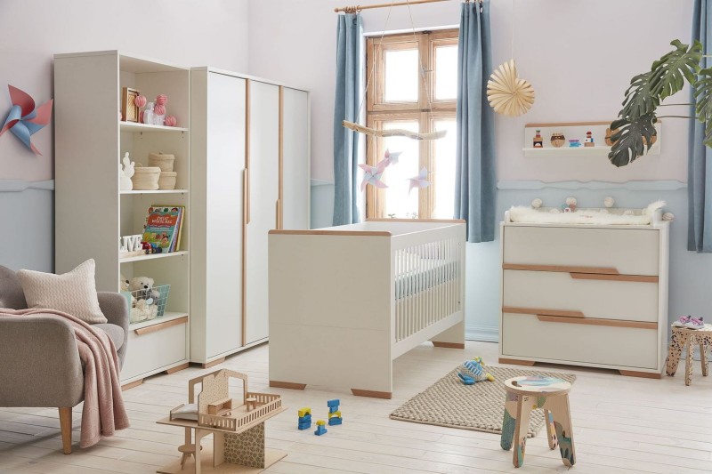 Biały zestaw mebli dziecięcych: łóżeczko, komoda z przewijakiem, szafa, regał, z drewnianymi akcentami.