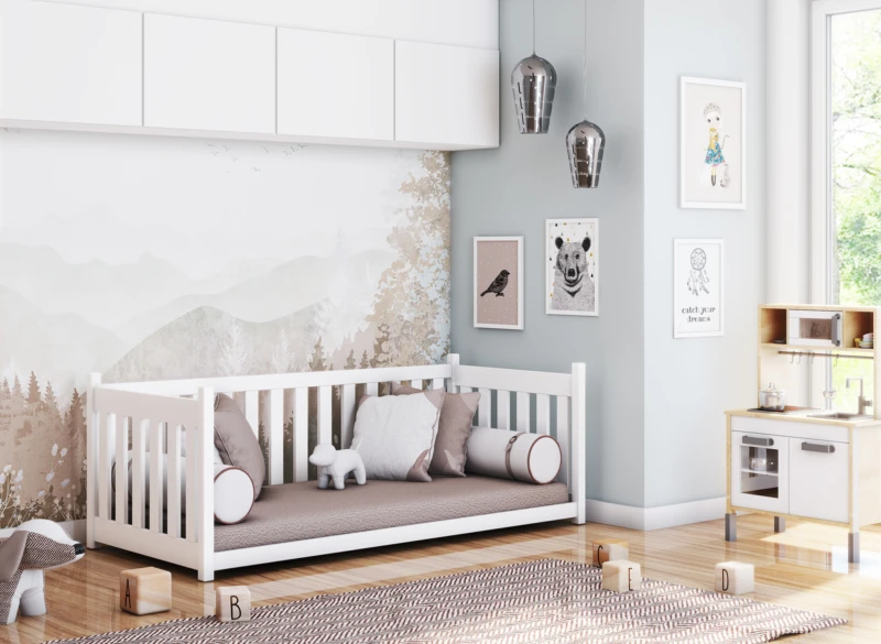 Białe drewniane łóżeczko dziecięce z poduszkami w pokoju dziecięcym z tapetą leśną i kuchnią zabawkową.