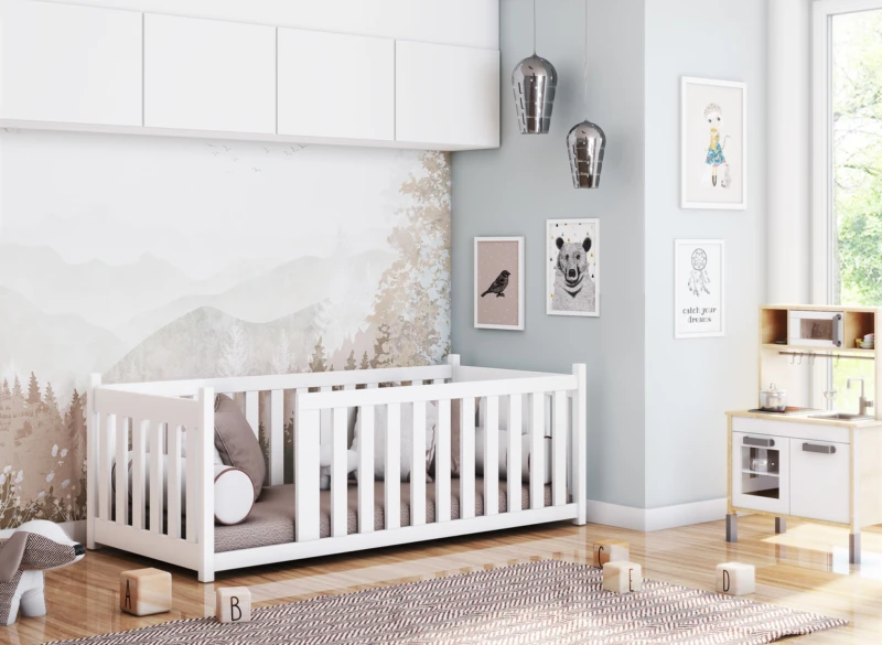 Pokój dziecięcy z białym łóżeczkiem, dywanem i drewnianą mini kuchnią.