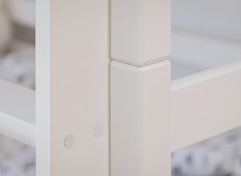 Zbliżenie na precyzyjne łączenie białej ramy łóżka piętrowego.