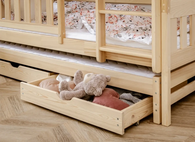 Szuflada pod łóżkiem piętrowym z pluszowym misiem i poduszkami.