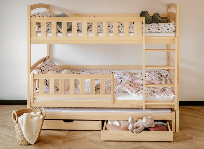 Drewniane łóżko piętrowe sosnowe z szufladami, w pokoju dziecięcym z jasnymi ścianami i podłogą.