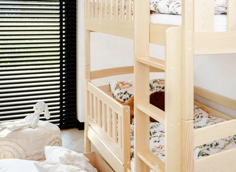 Drewniane łóżko piętrowe z bezpieczną drabinką i barierkami dla dzieci.