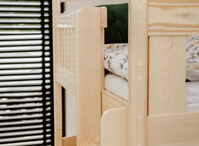 Zbliżenie na solidną barierkę i szczeble drabinki w drewnianym łóżku piętrowym dla dzieci.