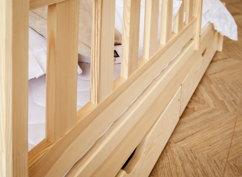 Solidna konstrukcja ramy łóżka z litego drewna sosnowego, widok z boku na szuflady.