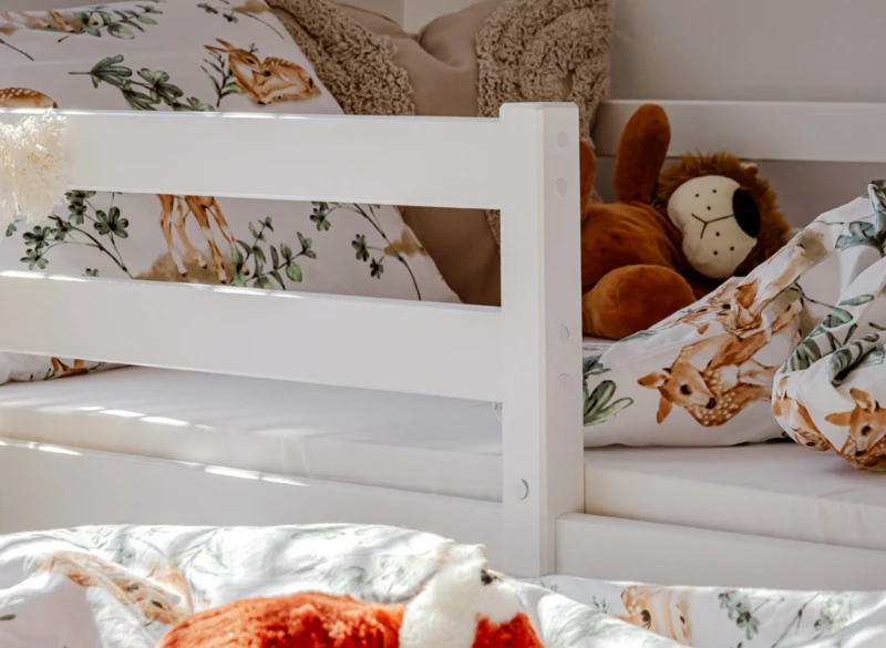 Barierka ochronna białego łóżka dziecięcego i urocza pościel w sarenki.