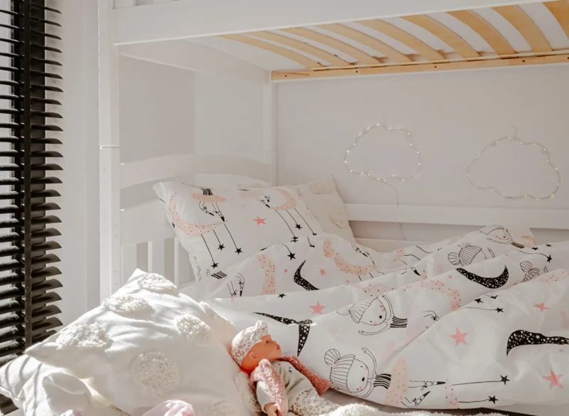 Pościel w baletnice na białym łóżku piętrowym w przytulnym pokoju dziecięcym.