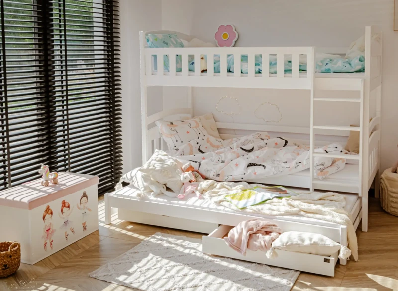 Białe łóżko piętrowe z wysuwanym trzecim spaniem i szufladami w pokoju dziewczynki.