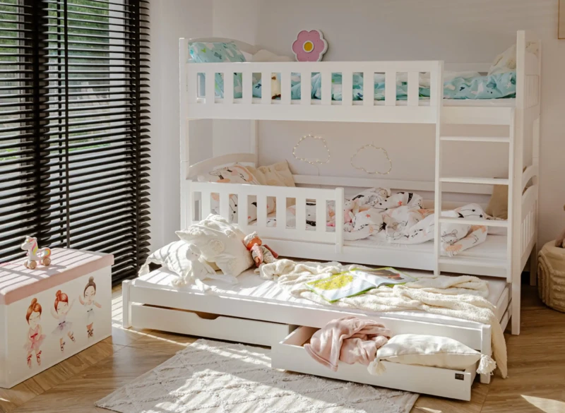 Wysuwane trzecie spanie i szuflady w białym łóżku piętrowym.