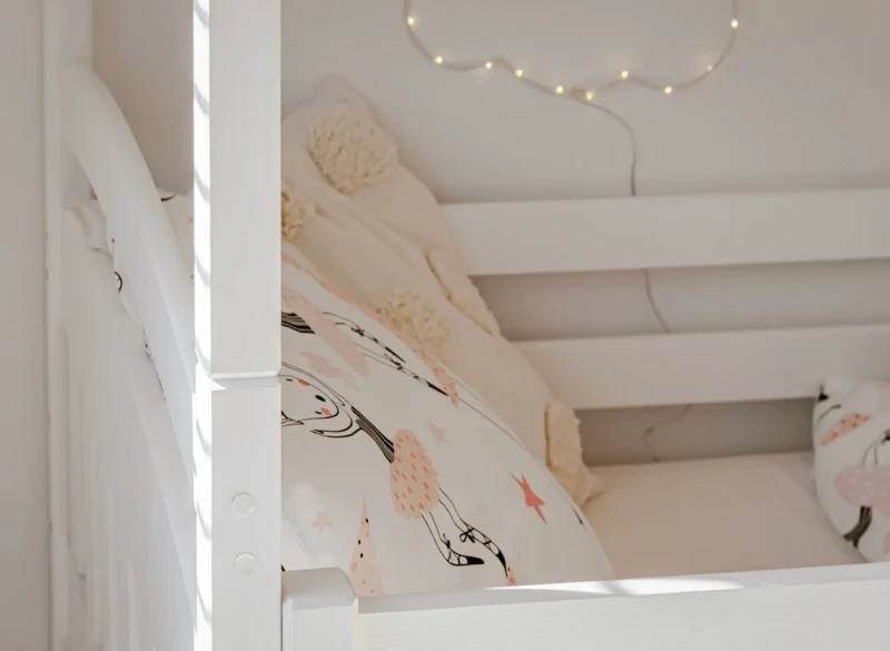Przytulna aranżacja środkowego poziomu łóżka piętrowego z lampką chmurką.