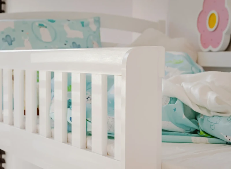 Detale wykończenia barierki ochronnej białego łóżka piętrowego.
