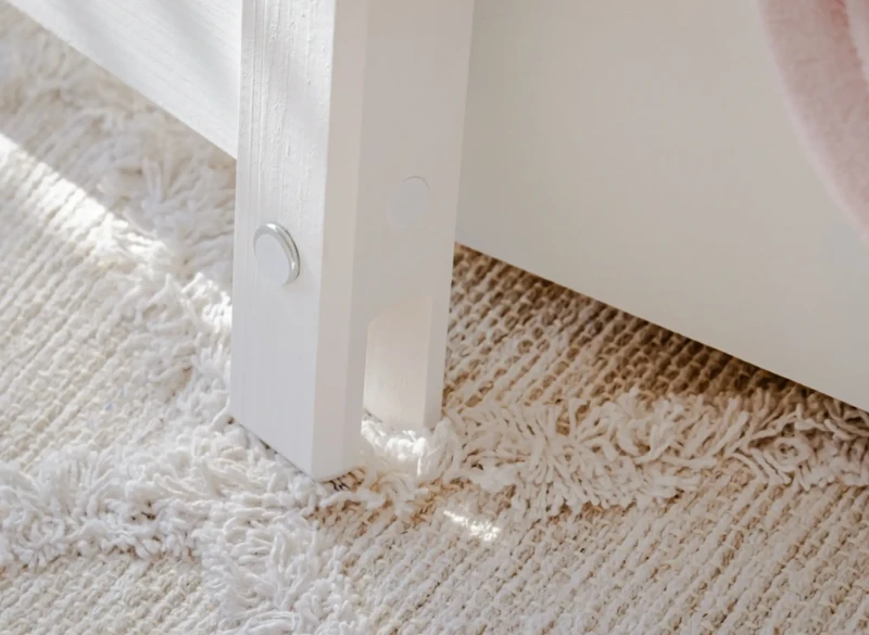 Detale wykończenia białego łóżka piętrowego z litego drewna.