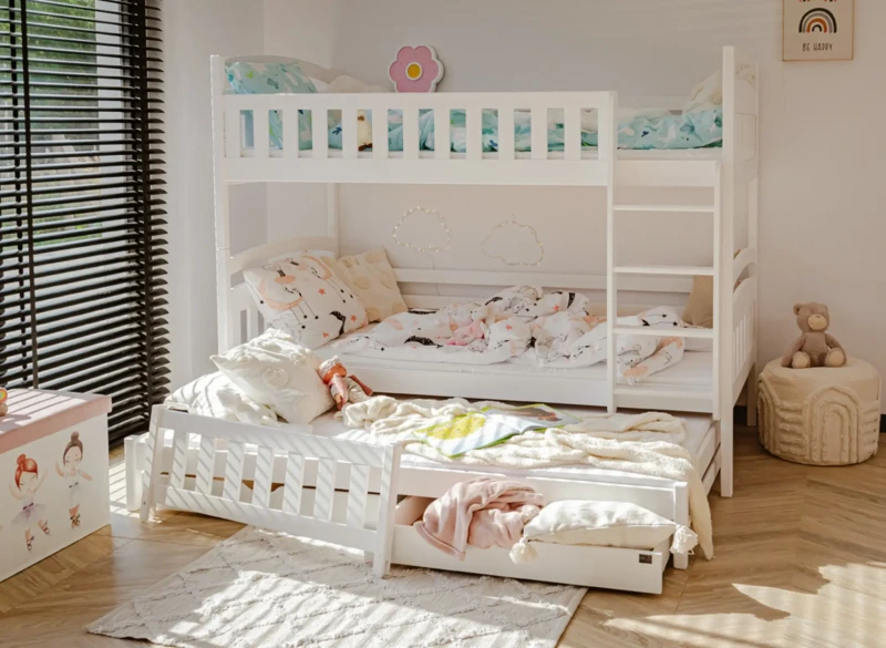 Pełny widok na białe trzyosobowe łóżko piętrowe z drabinką i wysuwanym spaniem.
