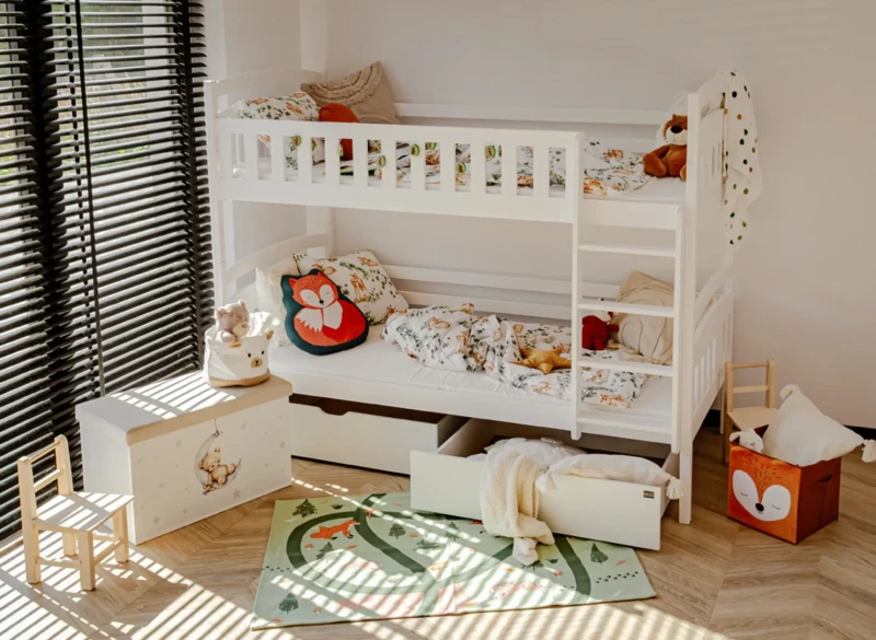 Aranżacja jasnego pokoju dziecięcego z białym łóżkiem piętrowym i dywanikiem.