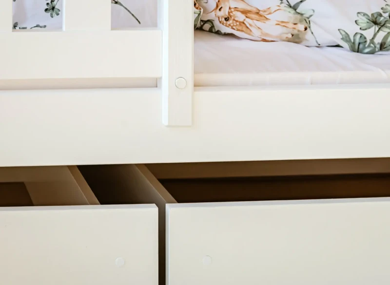 Detal wysuwanych szuflad pod łóżkiem piętrowym, idealnych do przechowywania zabawek.
