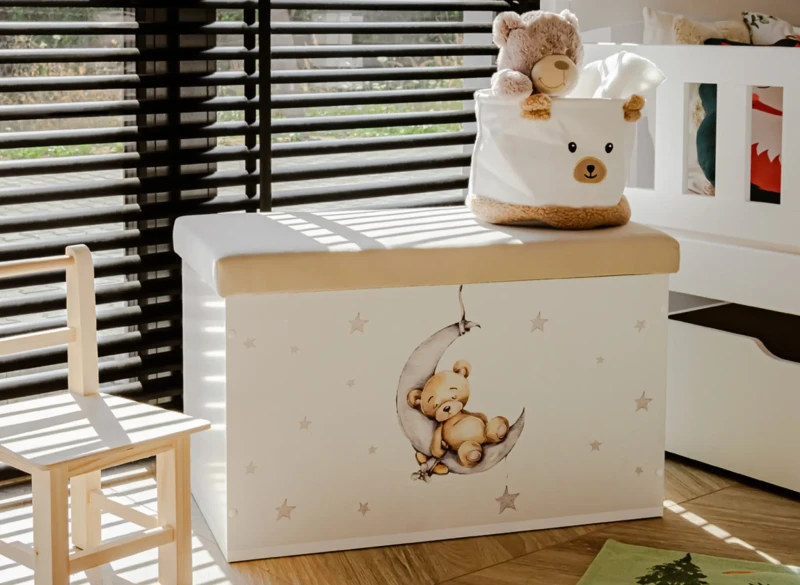 Biała skrzynia na zabawki z siedziskiem i uroczym motywem śpiącego misia na księżycu.