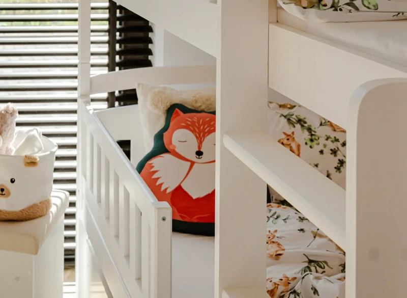 Barierka ochronna i drabinka białego łóżka piętrowego dla bezpieczeństwa.