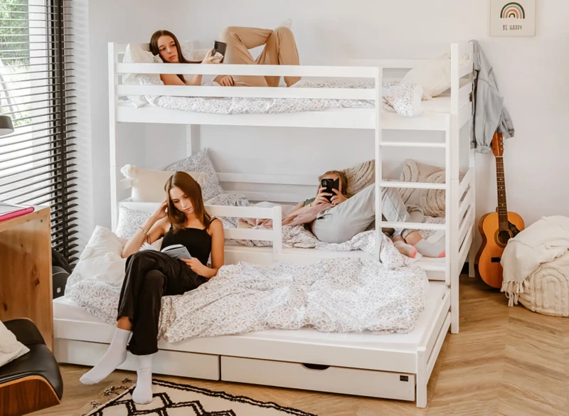 Białe łóżko piętrowe 3-osobowe z wysuwaną dostawką w nowoczesnym pokoju.