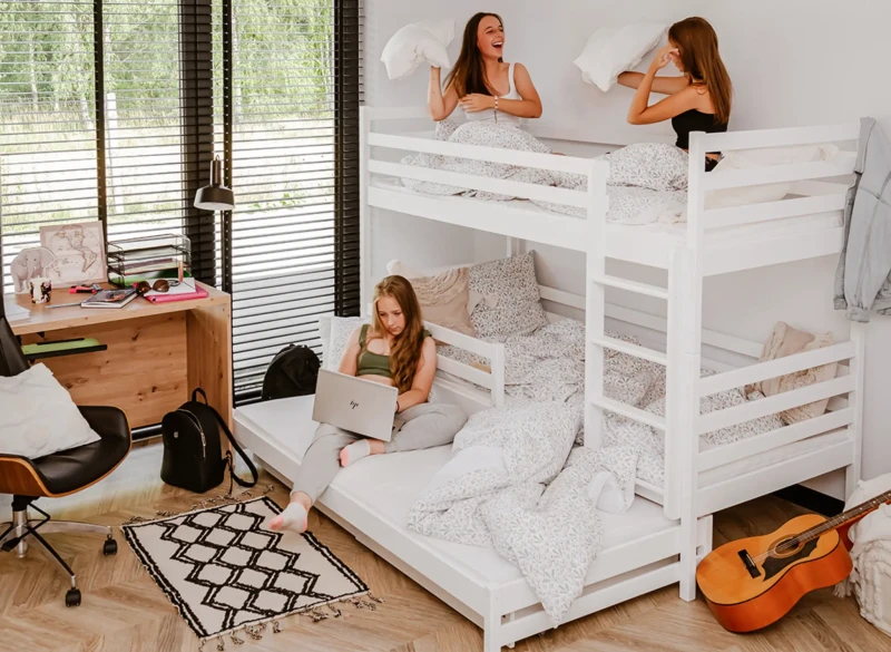 Zabawa i nauka na białym łóżku piętrowym trzyosobowym w pokoju młodzieżowym.
