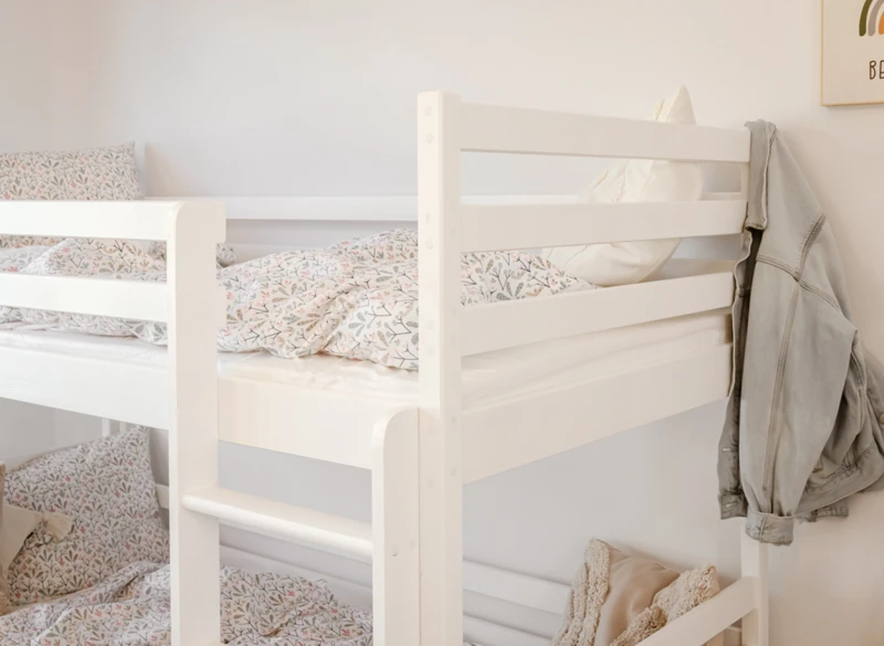 Górne barierki ochronne białego łóżka piętrowego dla dzieci.