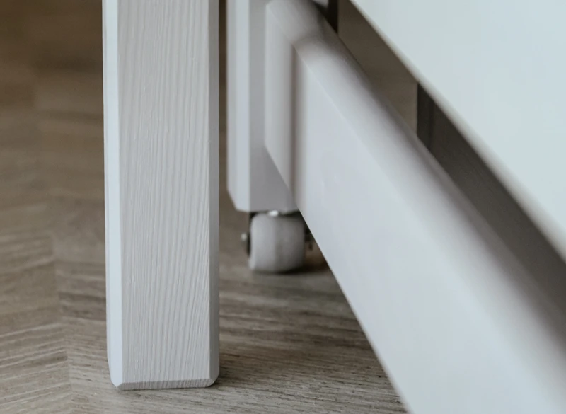 Detale konstrukcyjne nogi szarego łóżka dziecięcego z drewna.