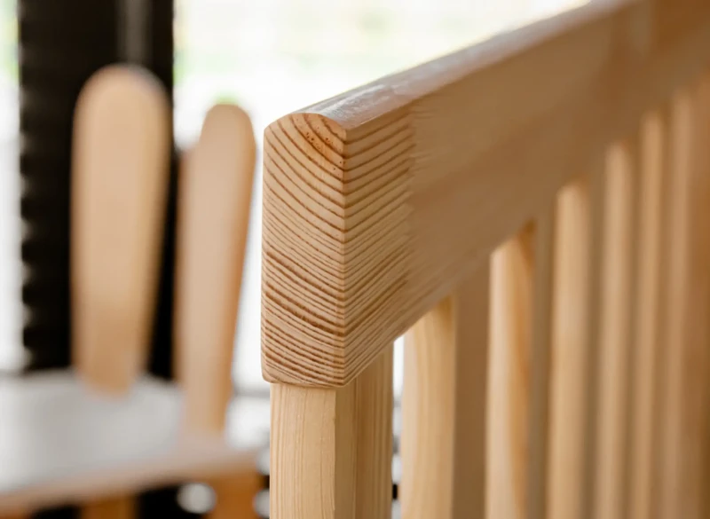 Bezpieczne, zaokrąglone krawędzie barierki ochronnej w dziecięcym łóżku z drewna.