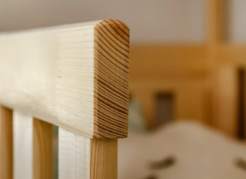 Zaokrąglone krawędzie drewnianego słupka łóżka, bezpieczne dla dziecka, naturalna sosna.