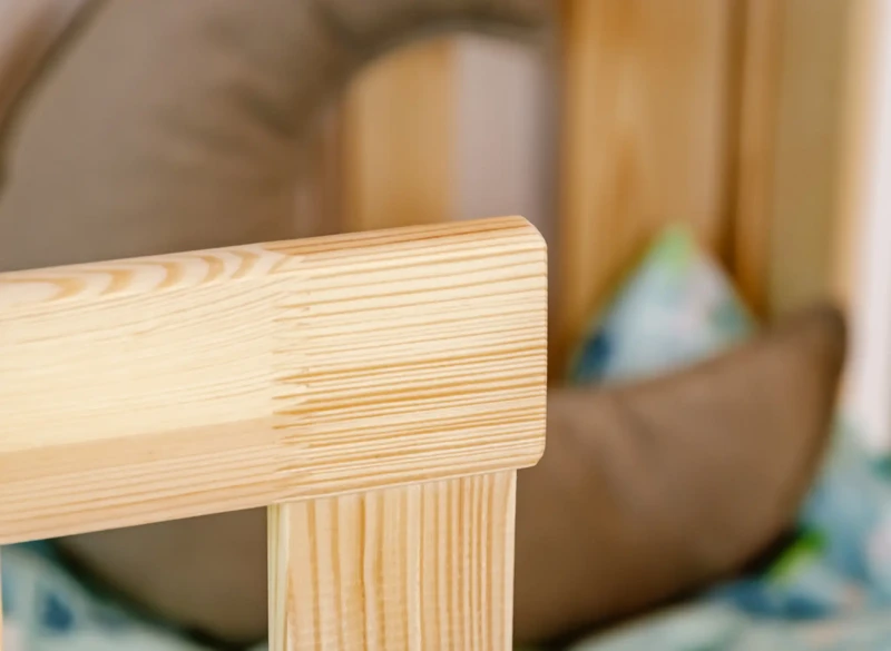 Staranne wykończenie krawędzi łóżka drewnianego, widoczne słoje naturalnego drewna.