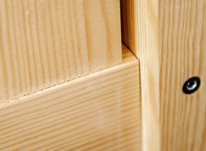 Zbliżenie na precyzyjne połączenie elementów łóżka piętrowego z naturalnego drewna.