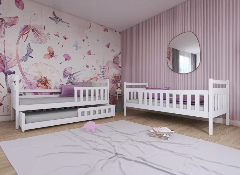 Białe łóżka dziecięce drewniane, jedno z wysuwanym materacem, w aranżacji pokoju z różowymi ścianami.