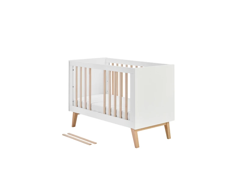 Białe łóżeczko niemowlęce ze szczebelkami i drewnianymi nóżkami