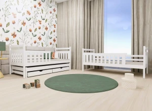 Białe drewniane łóżko młodzieżowe z szufladami i łóżeczko dziecięce w pokoju z tapetą w kwiaty.