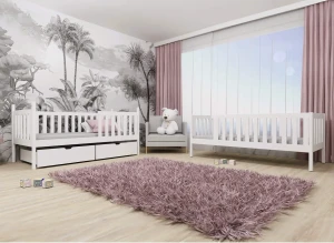 Białe drewniane łóżeczko dziecięce, proste i eleganckie, w pokoju malucha z tapetą w palmy i różowym dywanem.