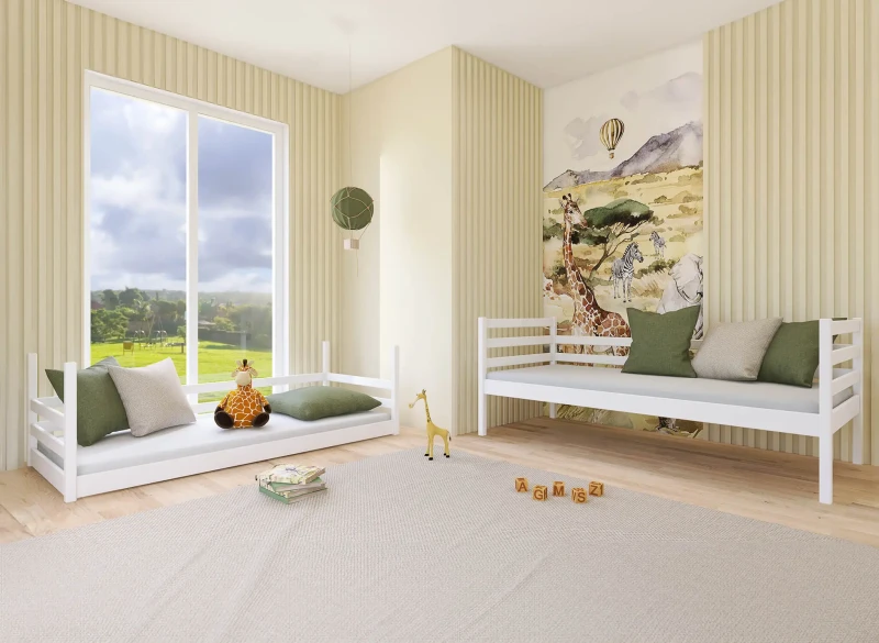 Dwa białe drewniane łóżka dziecięce w aranżacji pokoju safari z zielonymi poduszkami.