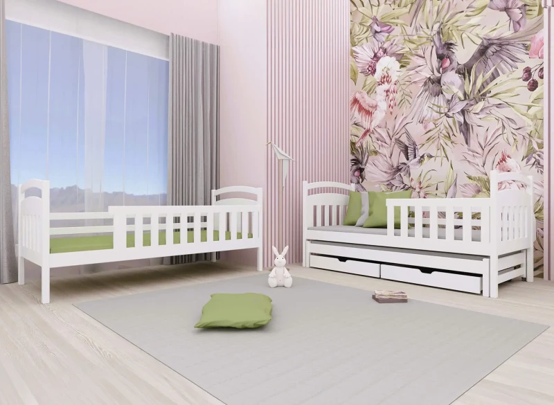 Białe drewniane łóżka dziecięce z wysuwanym spaniem i zielonymi materacami, w aranżacji pokoju z tapetą w ptaki.