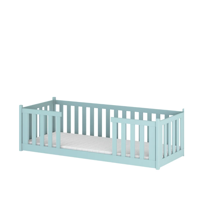 Jasnoniebieskie drewniane łóżko dziecięce z materacem, z barierkami, na białym tle.