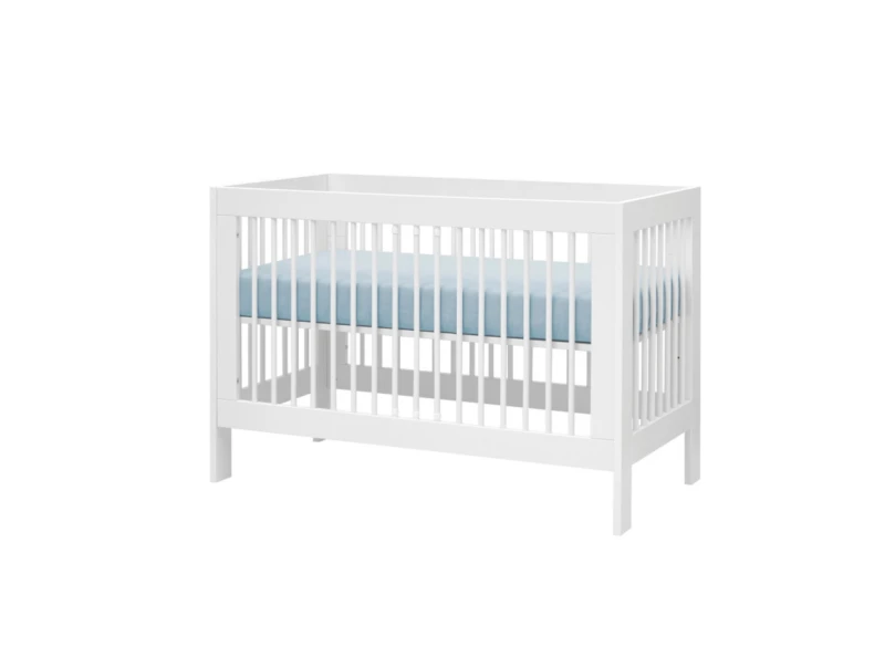 Białe łóżeczko niemowlęce ze szczebelkami i błękitnym materacem