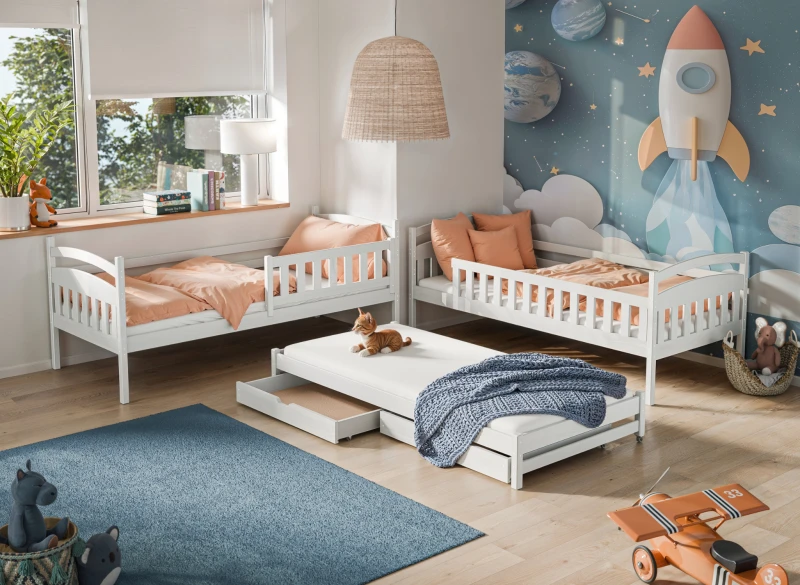 Białe drewniane łóżka dziecięce z wysuwanym materacem, pomarańczowa pościel, w pokoju z motywem kosmicznym.