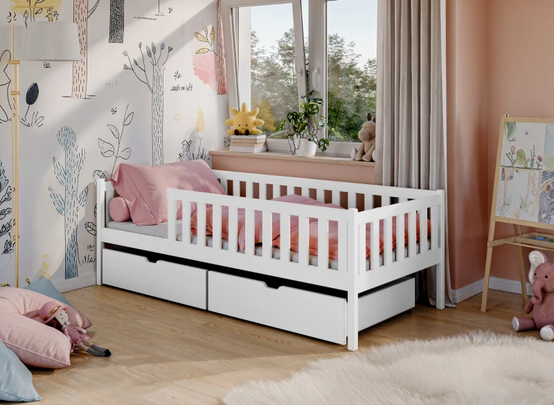Białe łóżko dziecięce z barierką i szufladami, z różową pościelą, w aranżacji pokoju dziecięcego.