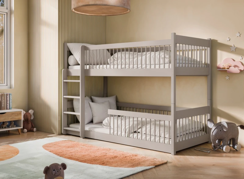 Szare drewniane łóżko piętrowe z barierkami i drabinką w aranżacji pokoju dziecięcego z beżowymi ścianami.