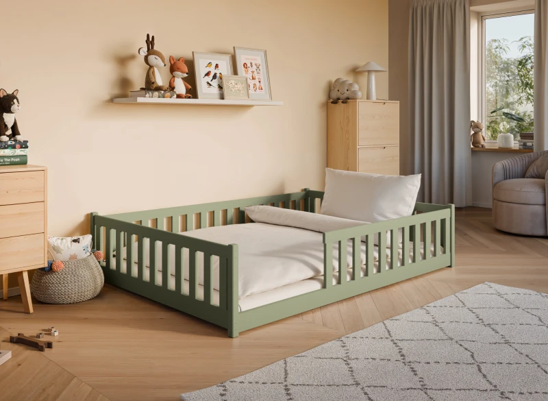 Zielone drewniane łóżko dziecięce z barierkami i białą pościelą w przytulnym pokoju.