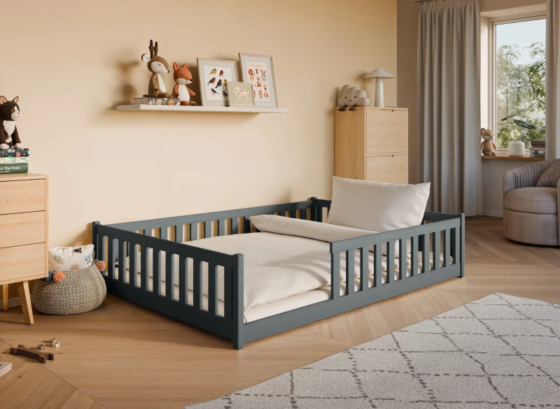 Szare łóżko dziecięce z barierkami, materacem i pościelą, drewniane, w aranżacji pokoju.