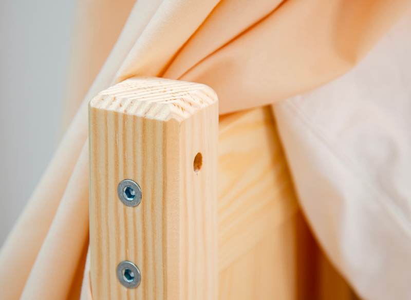 Zbliżenie na solidne łączenia śrubowe w konstrukcji drewnianego łóżeczka.