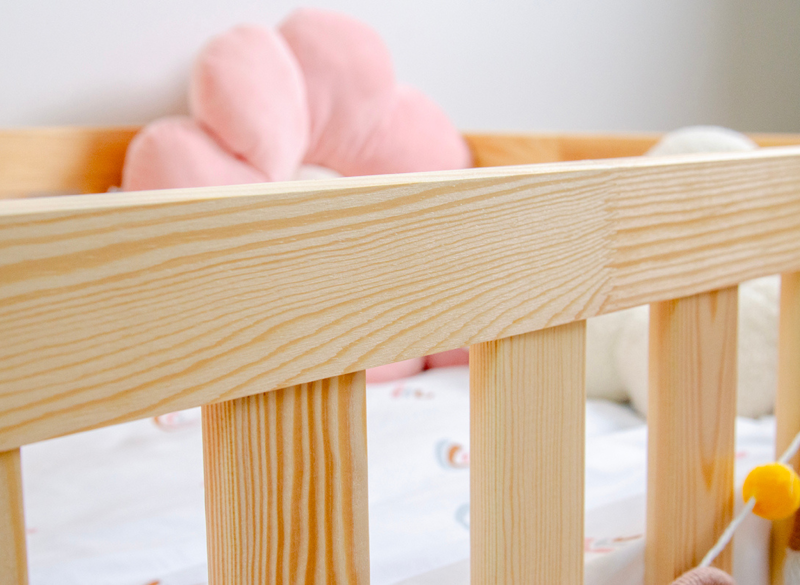Naturalna struktura drewna sosnowego na barierce ochronnej łóżka dla dzieci.