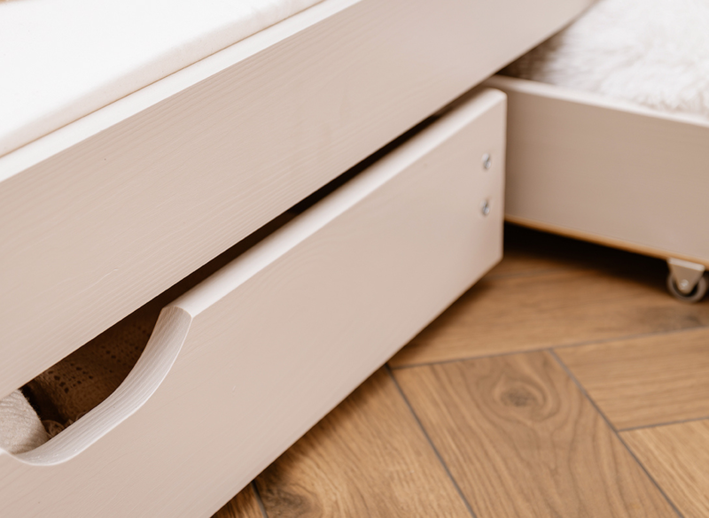 Funkcjonalny wycięty uchwyt białej szuflady pod łóżkiem dziecięcym.