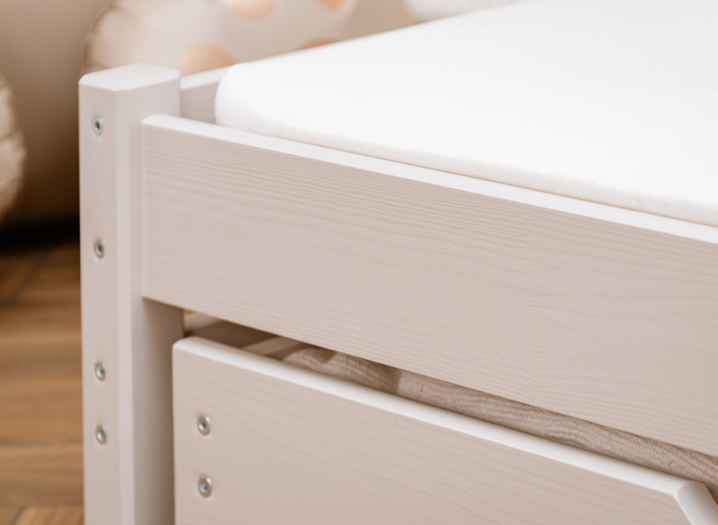 Zbliżenie na ramę białego łóżka drewnianego z widoczną teksturą drewna i śrubami.