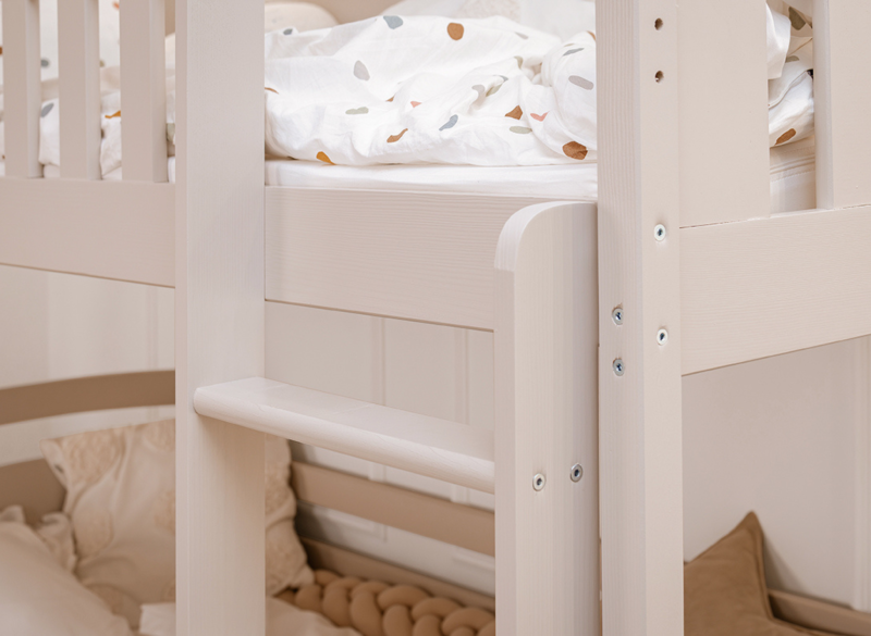 Bezpieczna drabinka do górnego łóżka w białym drewnianym modelu piętrowym.
