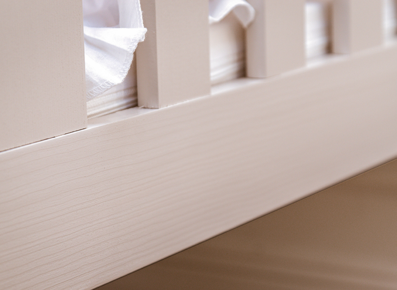 Zbliżenie na strukturę drewna sosnowego i kolor kaszmirowy łóżka dziecięcego.