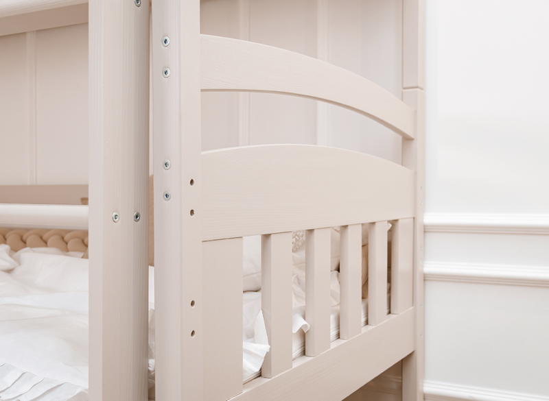 Detal barierki ochronnej jasnego łóżka piętrowego dla dzieci.