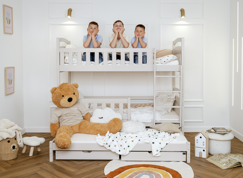 Trzej chłopcy na górnym poziomie białego łóżka piętrowego dla dzieci.